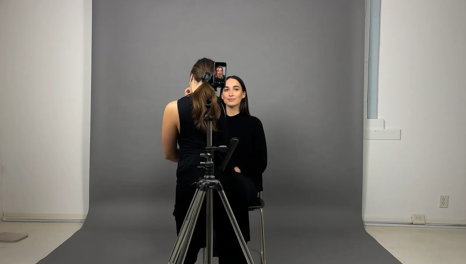 Artist photographing a client against a plain backdrop