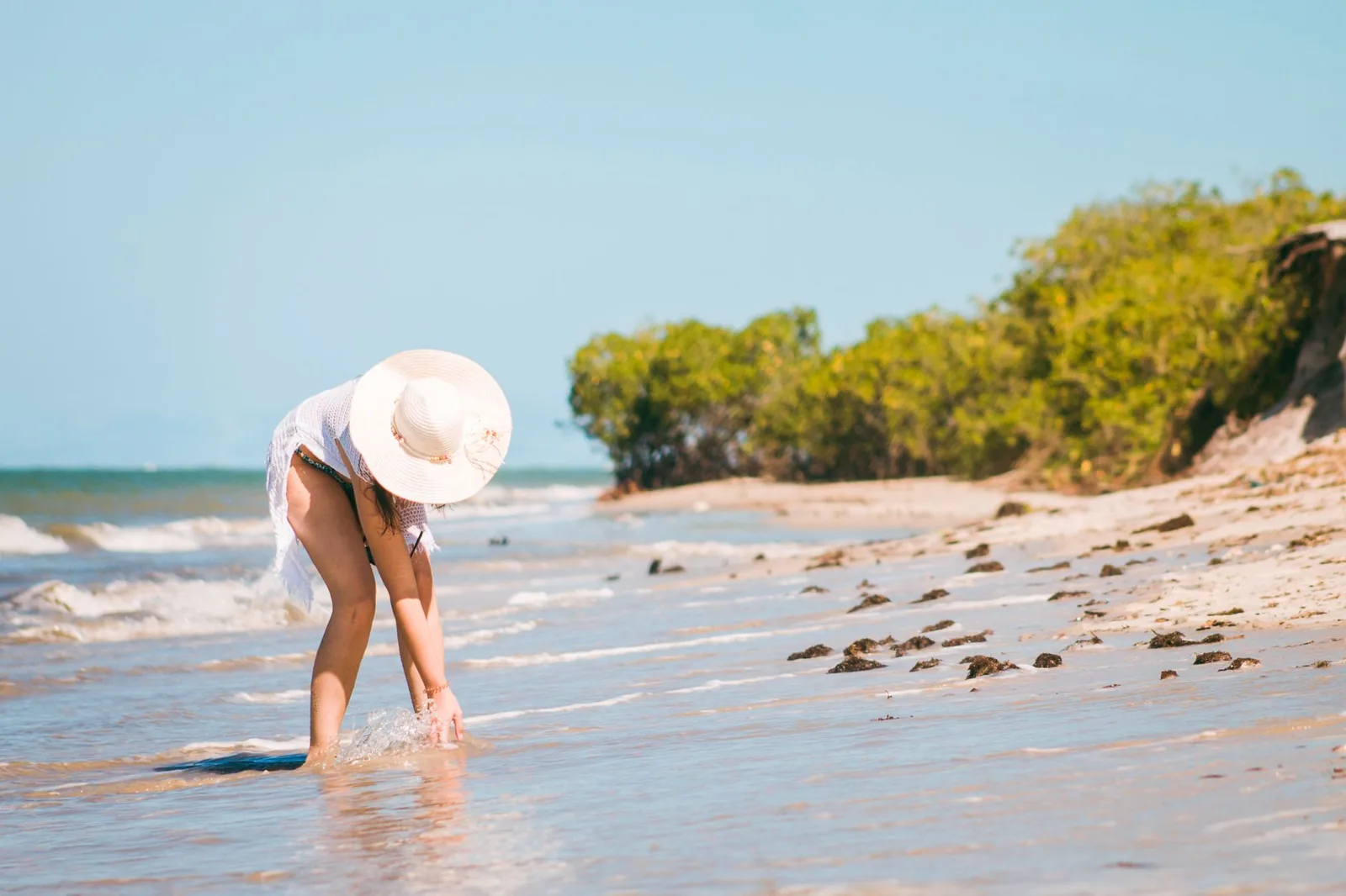 Woman in a wide sun hat at the edge of the sea