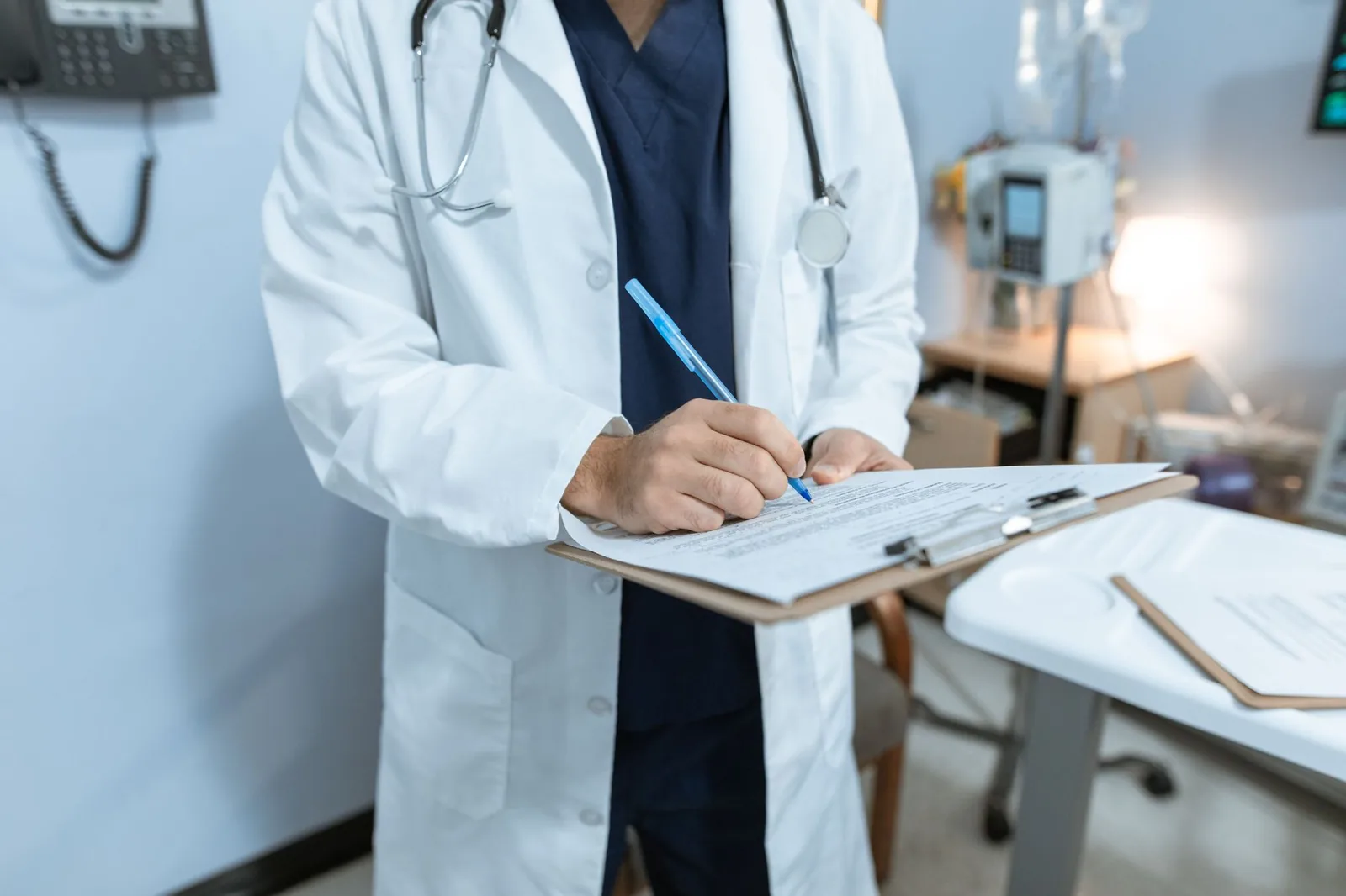 A doctor in a lab coat writing on a clipboard
