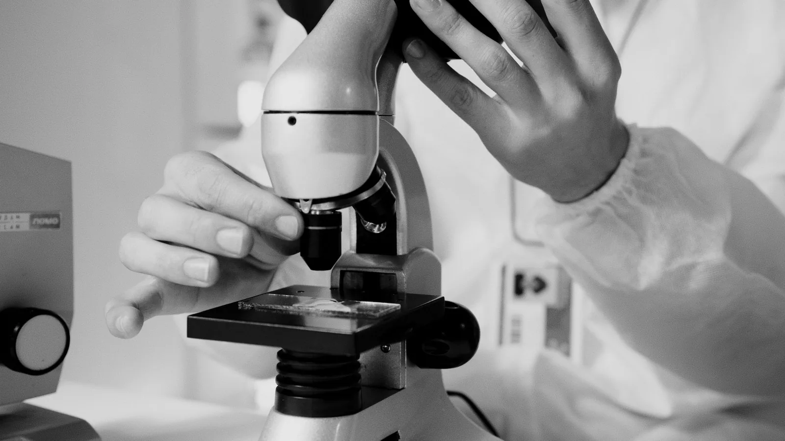A scientist in a lab coat using a microscope