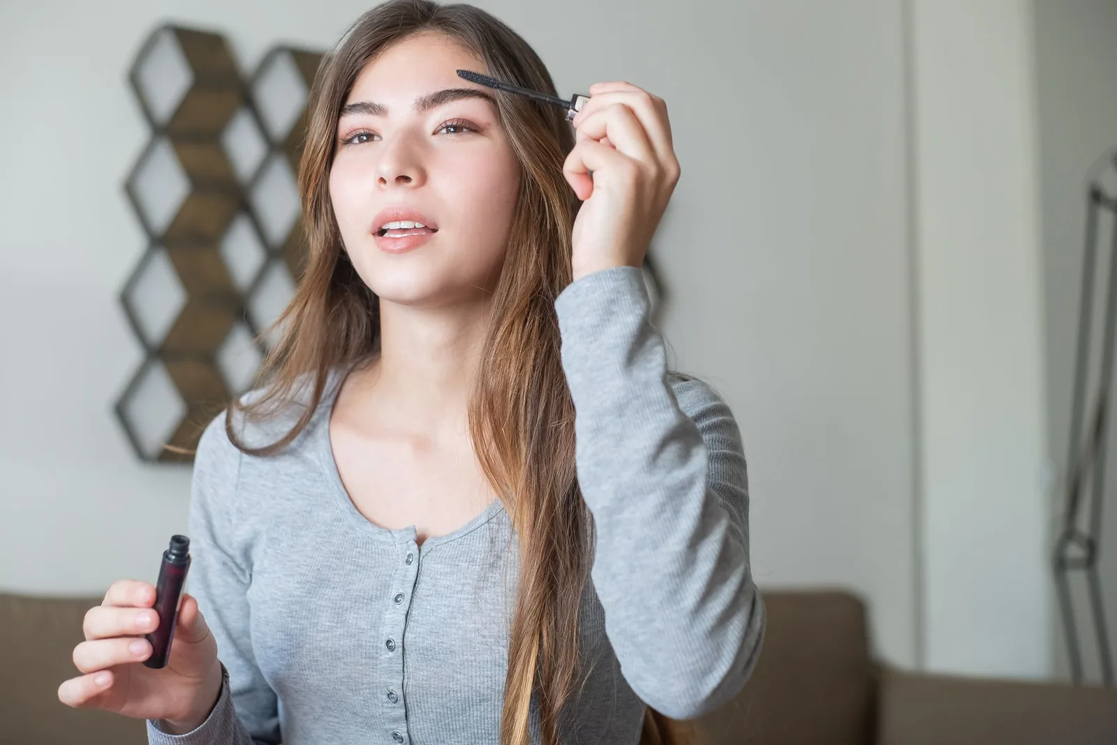 A woman brushing her eyebrow with a brow wand