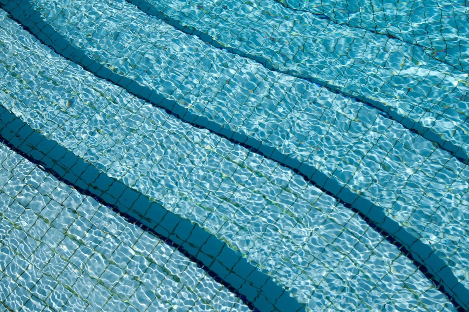Tiled swimming pool floor under clear water